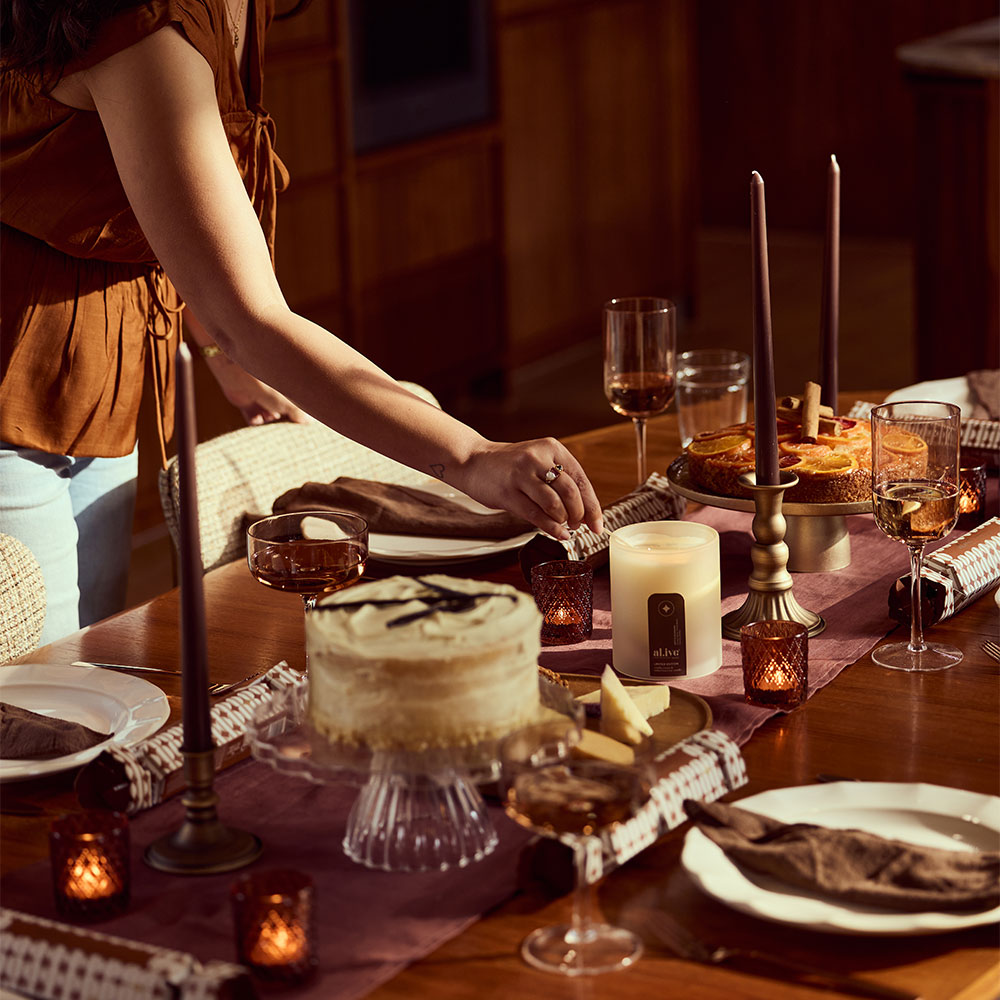 Christmas table set with a vanilla bean cream cake and an al.ive body Vanilla Cream & Tonka Bean Soy Candle